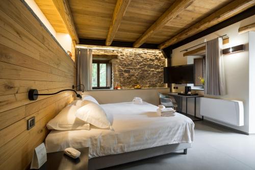 a bedroom with a white bed and a wooden wall at Borgotufi Albergo Diffuso in Castel del Giudice