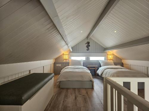 a attic bedroom with two beds and a bench at Skip Inn Strandhuisjes in Katwijk aan Zee
