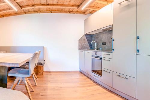 a kitchen with white cabinets and a wooden table at Berghütte Kneisl in Sölden