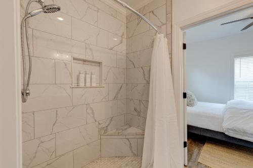 a bathroom with a walk in shower next to a bed at Mimosa Cottage - Thomasville Charm in Thomasville