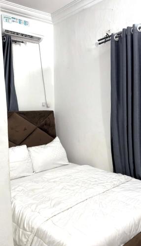 a bedroom with a bed with a blue curtain at AG Sigma Apartments in Port Harcourt