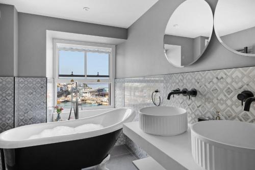 a bathroom with a tub and a sink and a mirror at Vigilance Suite - Free Wi-Fi - Sea View in Brixham