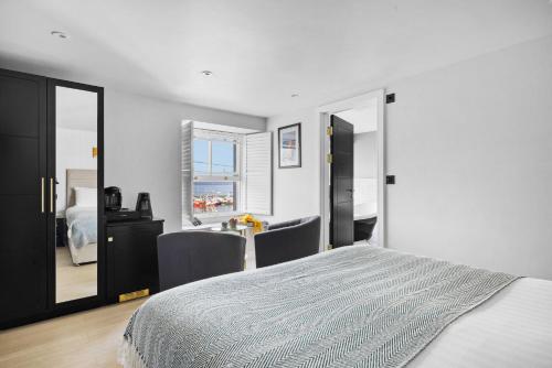 a white bedroom with a bed and a mirror at Vigilance Suite - Free Wi-Fi - Sea View in Brixham