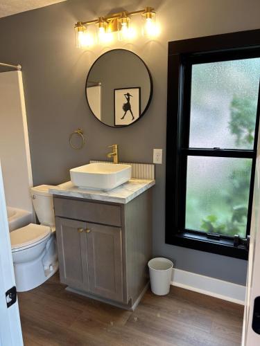 a bathroom with a sink and a mirror and a toilet at Victorian Queen Getaway Unit C Washerdryer in Muskegon