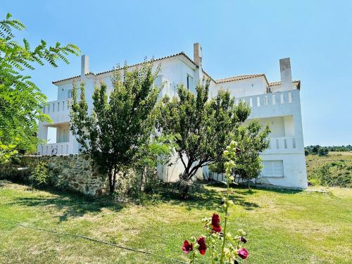 a large white house with trees in front of it at Mountain pool house in Varnávas