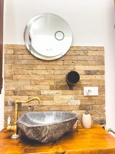a bathroom with a stone sink and a mirror at Corte Lirice Paradiso in Gioia del Colle