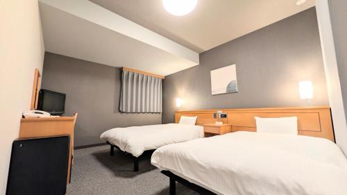 a hotel room with two beds and a television at Hotel Route-Inn Aomori Ekimae in Aomori