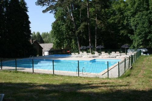 a swimming pool with white chairs and umbrellas at ZEcamping 3 étoiles chiens acceptés animations piscine chauffée in Grand-Laviers