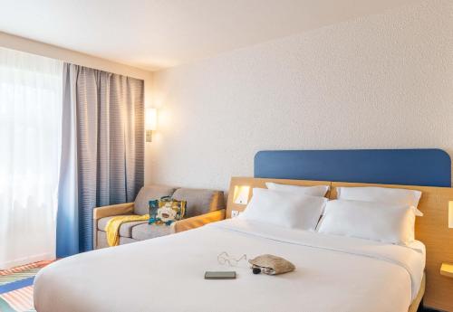 a hotel room with a bed and a chair at B&B HOTEL Lyon Nord 4 étoiles in Dardilly