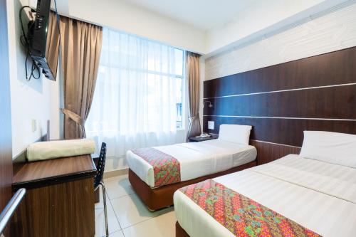a hotel room with two beds and a television at Sipadan Inn 3 in Semporna