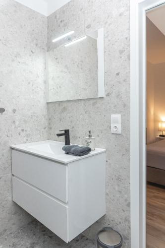 a white bathroom with a sink and a mirror at Infinity Stay Apartmenthaus am Park in Wilhelmshaven