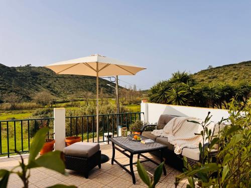 a patio with a couch and an umbrella and a table at Casa Nabia - Coastal Sanctuary in Ericeira