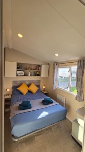 a bedroom with a large blue bed with yellow pillows at Tea & Toast Cottage Seton Sands in Port Seton