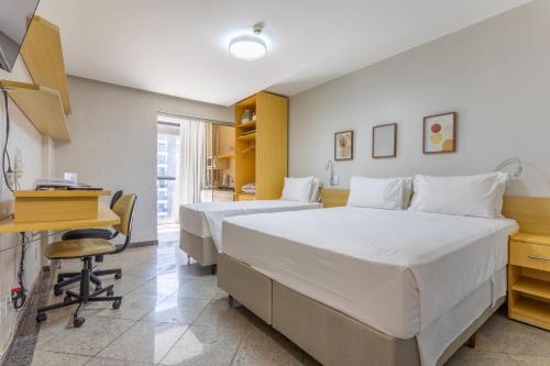 a hotel room with two beds and a desk and a desk at Flat - Excelente localização - Hotel Garvey in Brasília