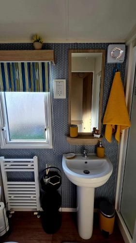 a bathroom with a sink and a mirror and a window at Tea & Toast Cottage Seton Sands in Port Seton