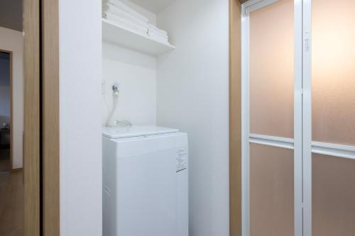 a white refrigerator in a room with a glass door at Bio Top Apartment Stay in Fukuoka