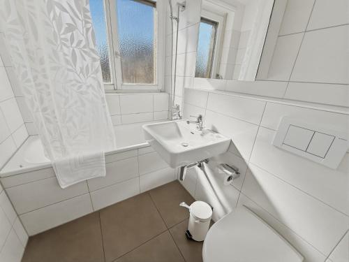 a white bathroom with a sink and a toilet at Cozy 1BR near lake with balcony - Mill 422 in Zurich