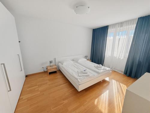 a white bedroom with a bed and a wooden floor at Cozy 1BR near lake with balcony - Mill 422 in Zurich