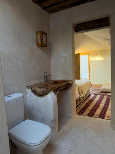 a bathroom with a toilet and a sink and a bedroom at Hidden Garden House in Siwa