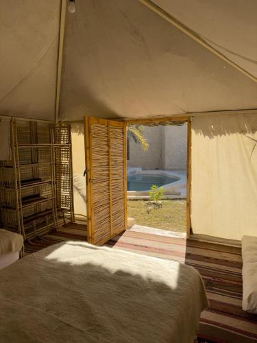 a tent with a bed in a room with a window at Hidden Garden House in Siwa