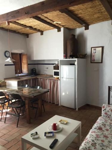 cocina con mesa y nevera blanca en La Casa del Bachiller, en Campo de Criptana