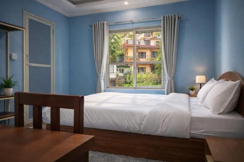 una camera da letto con un grande letto bianco e una finestra di The Mango Tree Backpackers Hostel a Pokhara