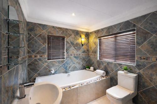 a bathroom with a tub and a toilet at Caesars Place Guest House in Kathu