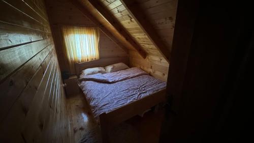 a small bed in a wooden cabin with a window at Koliba Bajka in Bijelo Polje