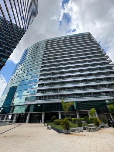 a tall glass building with trees in front of it at Fusion e Vision Flats in Brasília