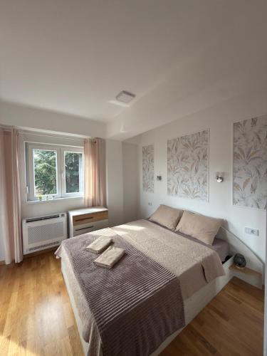 a bedroom with a large bed and two windows at KRUM Apartments in Kumanovo
