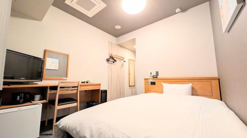 a bedroom with a bed and a desk and a television at Hotel Route-Inn Aomori Ekimae in Aomori