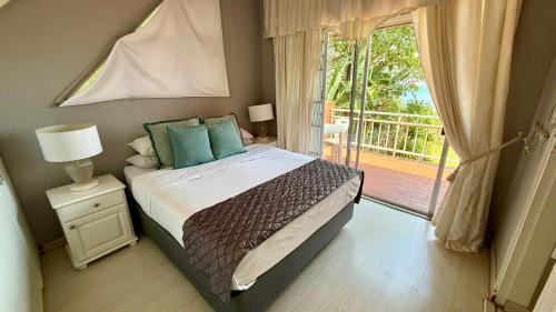 a bedroom with a large bed and a balcony at Karlin #2, Frontline, Beach Access, Scottburgh in Freeland Park