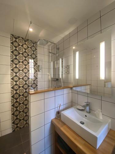 a white bathroom with a sink and a mirror at Hotel Au Cerf in Riquewihr