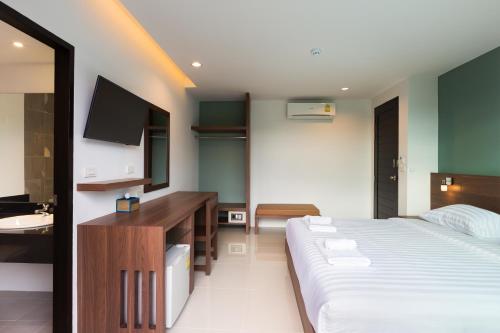 a bedroom with a bed and a sink and a television at Parida Resort in Bang Tao Beach