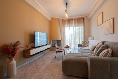 a living room with a couch and a flat screen tv at Aeris Apartment by Booking Kottas in Nea Moudania