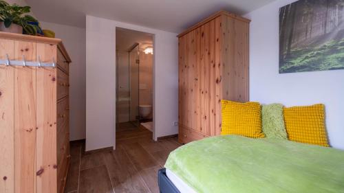 a bedroom with a green bed and wooden cabinets at Relax Walding in Jörgensbühl