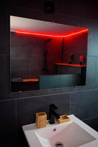 a bathroom mirror with a sink and a red light at L'Envers SPA - Suite Romantique Metz Centre in Metz