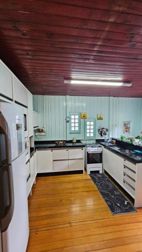 a large kitchen with white appliances and wooden floors at Casa Privativa no Centro de Urubici - Casa Doce Luar in Urubici