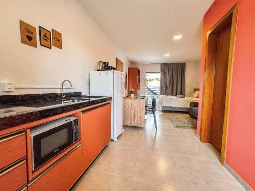 a kitchen with orange cabinets and a white refrigerator at Centro | Studio Completo até 4 pessoas in Brusque