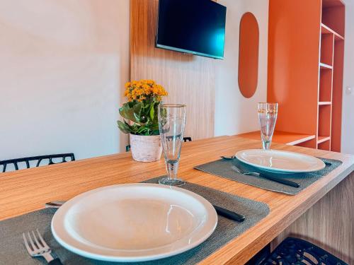 a wooden table with two plates and glasses on it at Centro | Studio Completo até 4 pessoas in Brusque