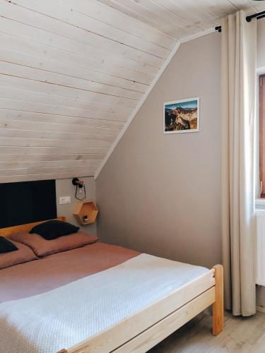 a bed in a bedroom with a wooden ceiling at Domek Sielski Zakątek Pieniny in Szczawnica