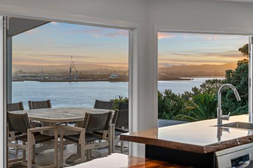 a kitchen with a table and a view of the water at Reotahi Bolthole in Whangarei Heads