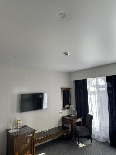 a hotel room with a tv and a desk and a chair at Optima Collection Bergshloss Rivne in Rivne