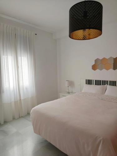 a white bedroom with a large bed and a chandelier at Living Sevilla & Parking gratis in Seville