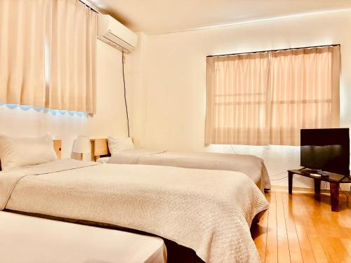 a room with two beds and a flat screen tv at バス停"平城札所前"徒歩0分 四国愛媛の宿 "40番たっきゅうミニホテル" "No40 Takkyu mini hotel" in Hirajō