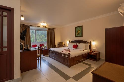 a bedroom with a bed and a desk and a window at Las Palmas in Munnar