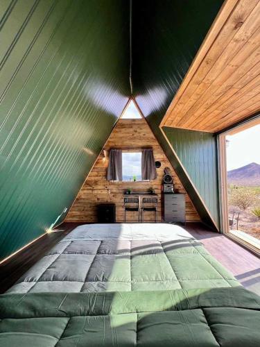 a large bed in a green room with a window at Starwalk Modern A-Frame #1 in Meadview