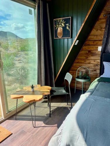 a bedroom with a bed and a table and a window at Starwalk Modern A-Frame #1 in Meadview