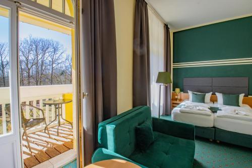 a hotel room with a bed and a green chair at Ferien Hotel Villa Südharz in Sülzhayn