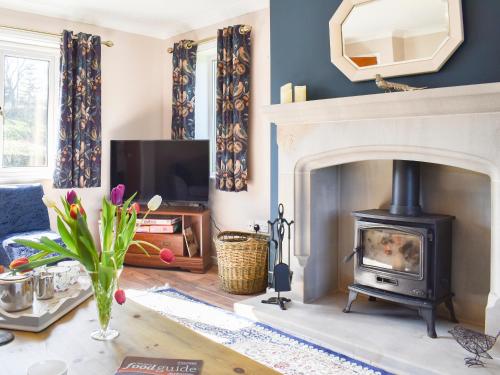 a living room with a fireplace and a tv at Mill Lea Cottage in Leek
